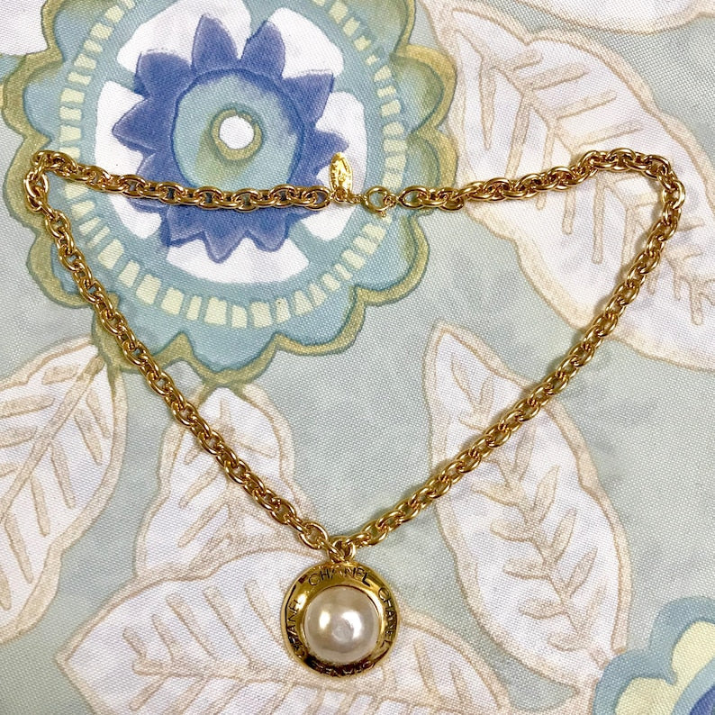 CHANEL Vintage golden chain necklace with round faux pearl and logo embossed charm