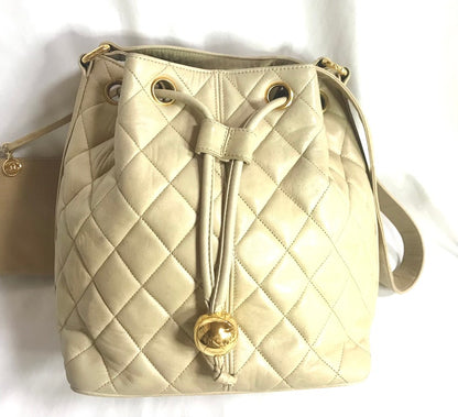 CHANEL Vintage beige quilted lamb leather hobo bucket shoulder bag with drawstrings and golden CC mark ball