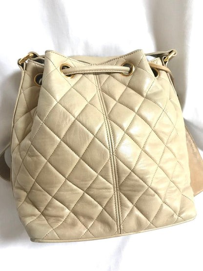 CHANEL Vintage beige quilted lamb leather hobo bucket shoulder bag with drawstrings and golden CC mark ball